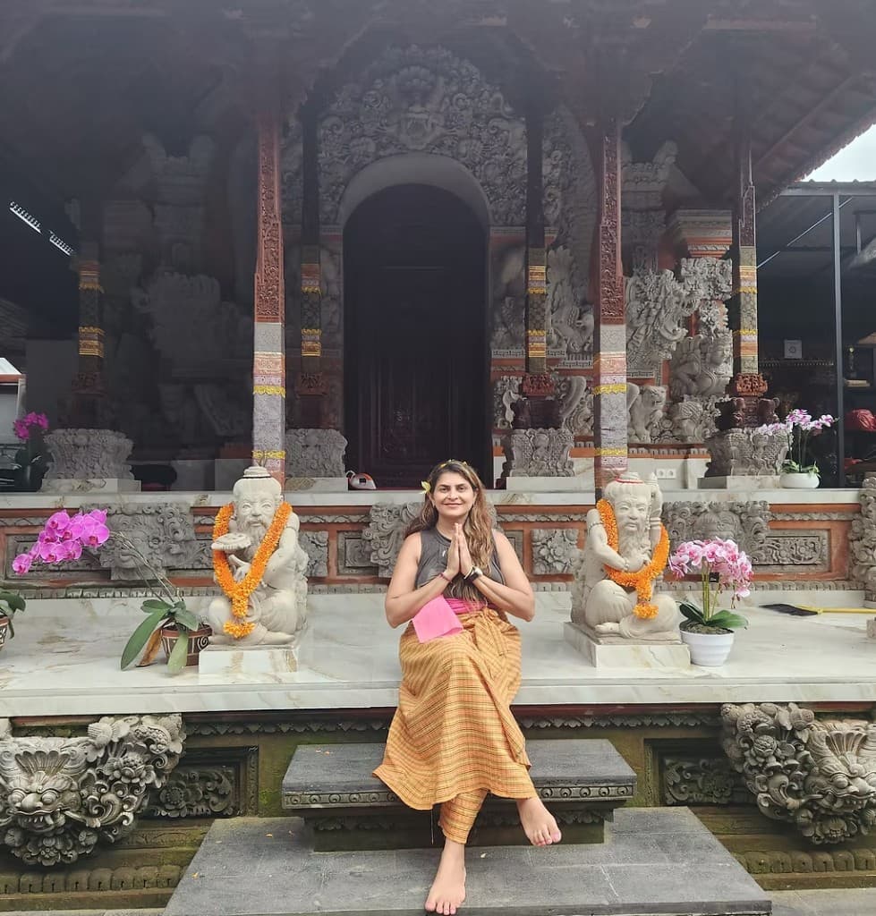Dr. Deepa Pattani seated in meditation at a Balinese temple
