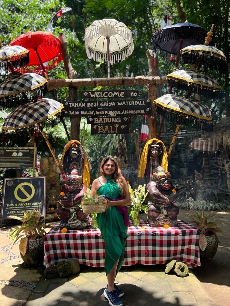 Woman holding flower offerings at the Taman Beji Griya Waterfall entrance in Badung, Bali