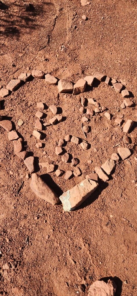 Heart-shaped spiral arranged from red rocks on desert ground in Sedona