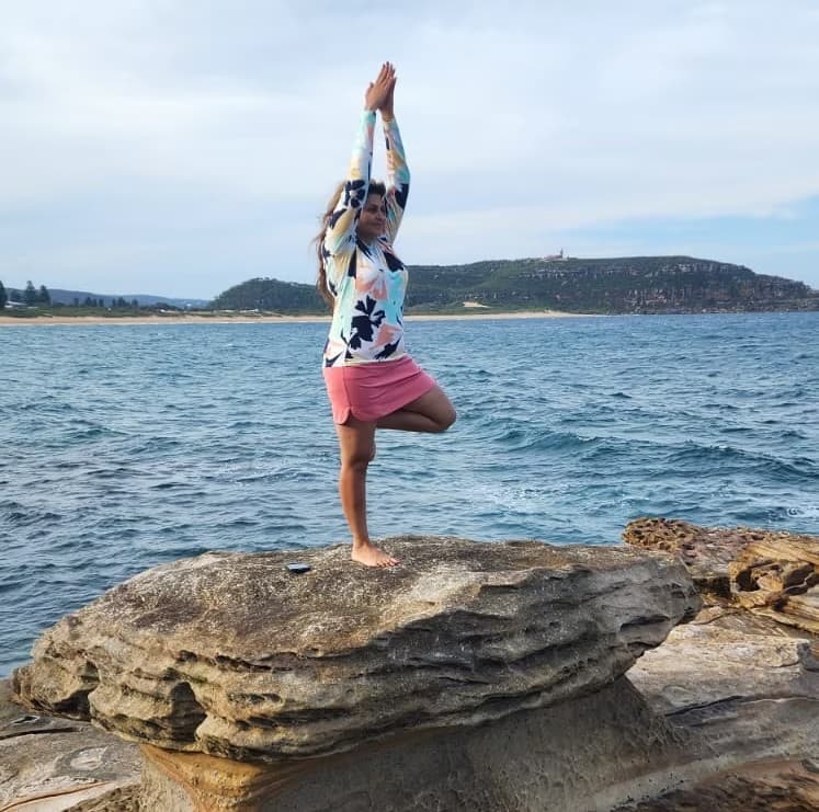 Dr. Deepa Pattani practicing tree pose by the ocean